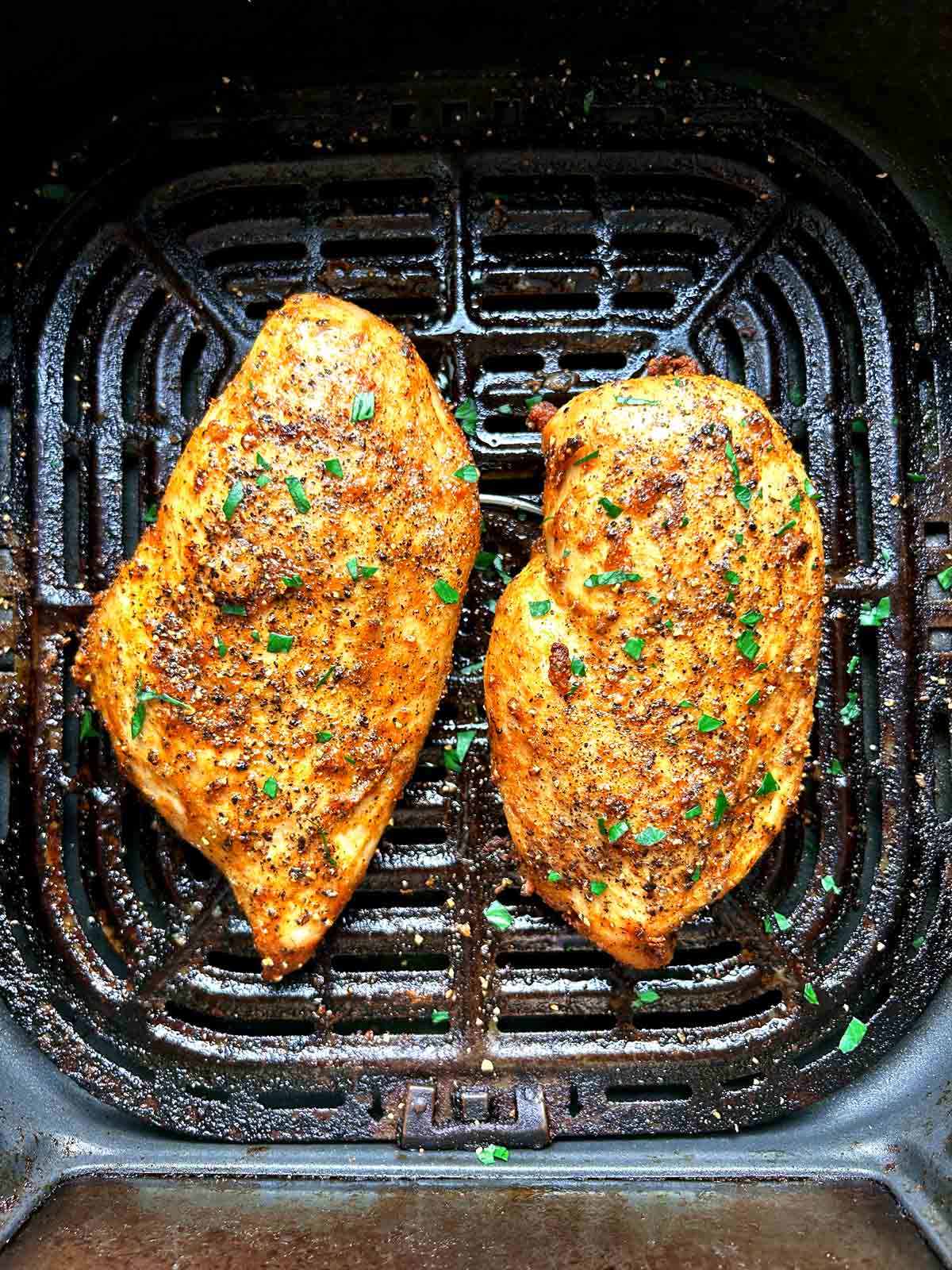 air fried chicken breasts in basket with parsley sprinkled on top.