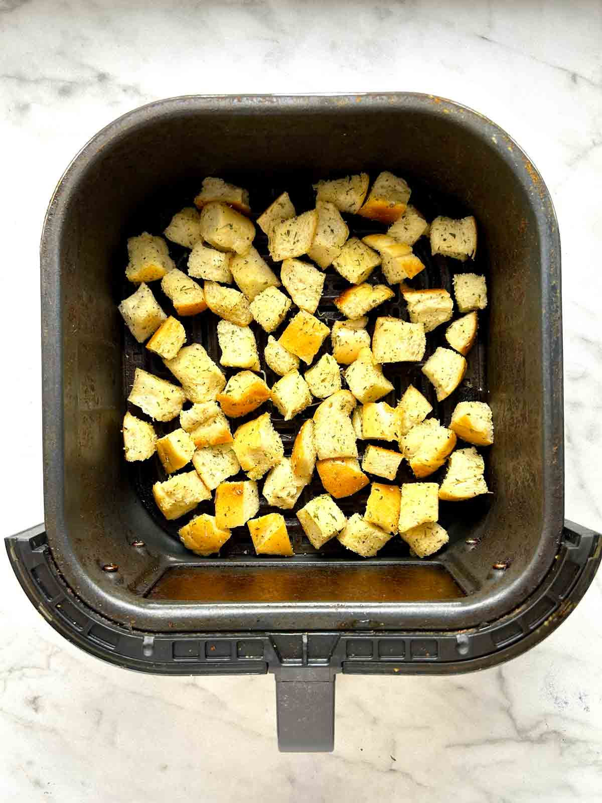 bread cubes arranged in air fryer basket.