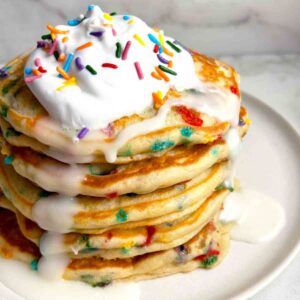 close up of birthday cake pancakes with whipped cream and vanilla icing.