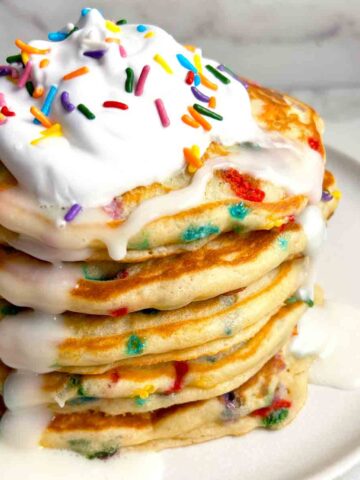 close up of birthday cake pancakes with whipped cream and vanilla icing.