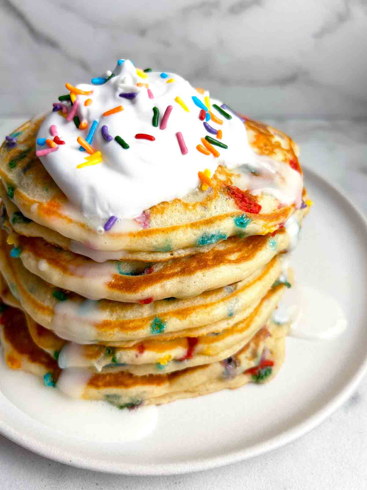 close up of birthday cake pancakes with whipped cream and vanilla icing.