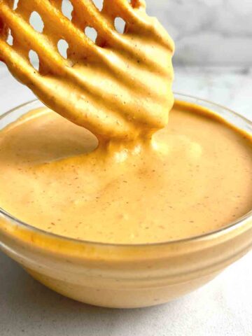waffle fry being dipped in chipotle sauce.