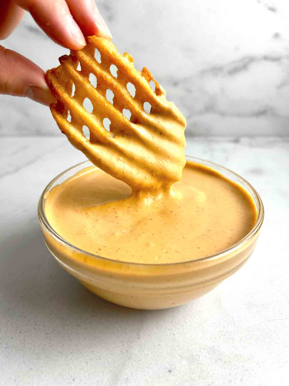 waffle fry being dipped in chipotle sauce.