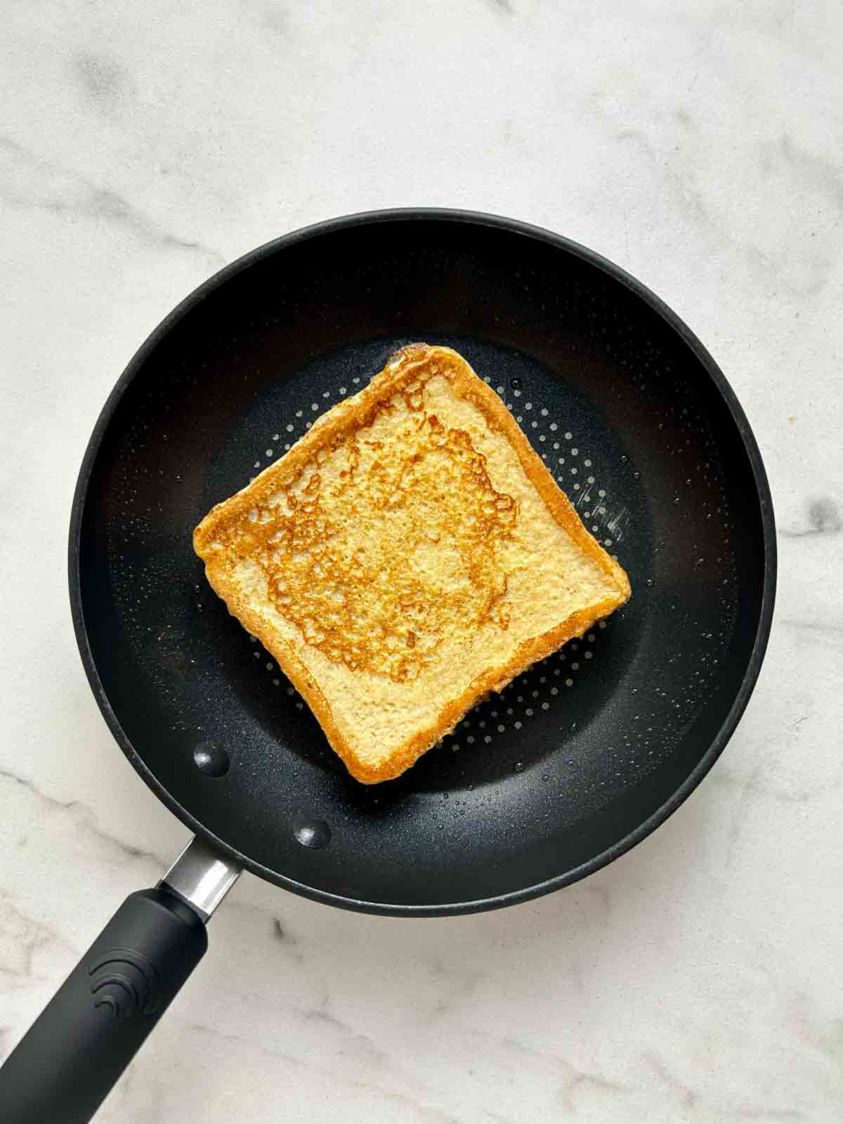 second side of toast cooking in pan.