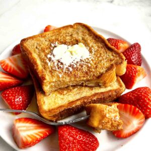 plate of French toast with strawberries on side.
