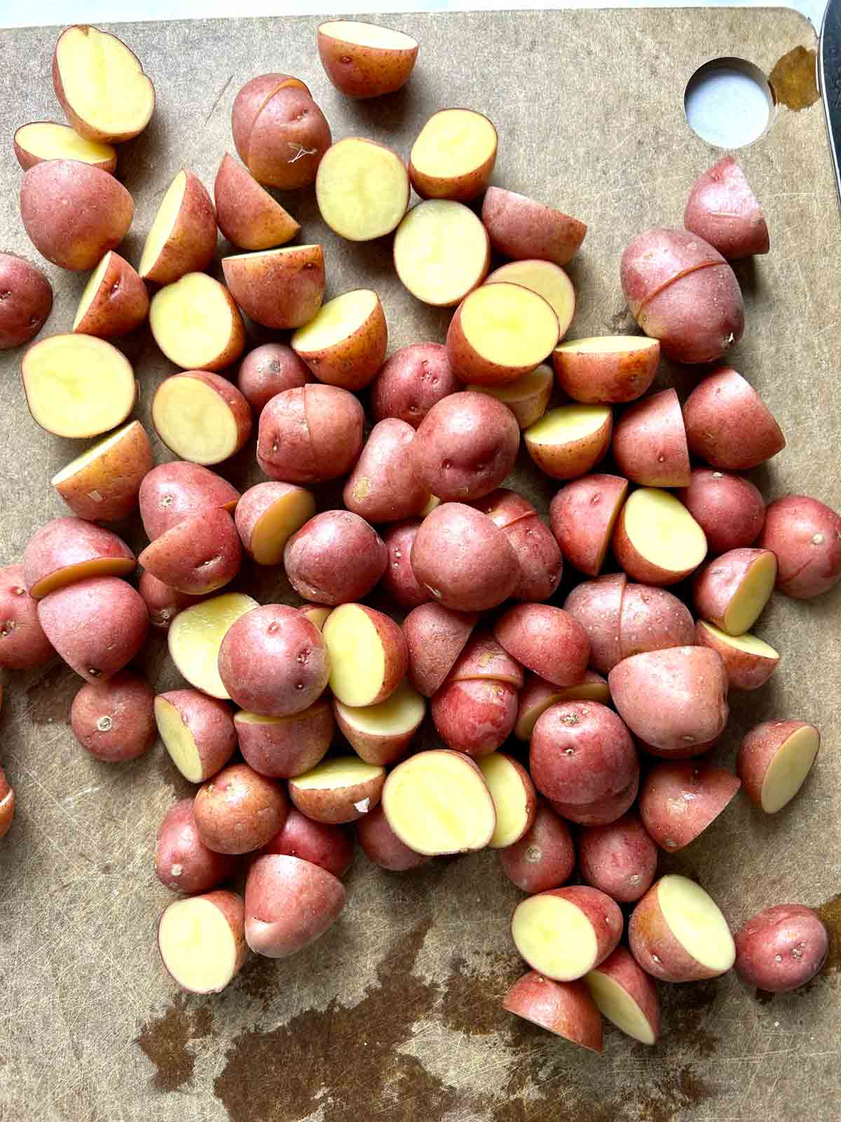 mini red potatoes chopped in half on cutting board.