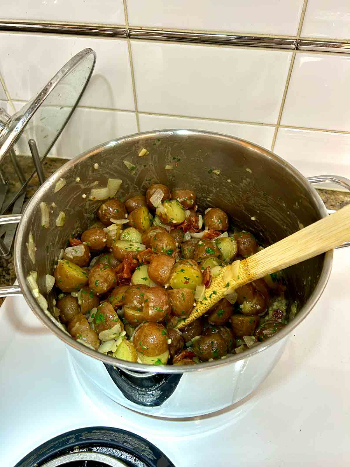 potatoes tossed with vinaigrette, parsley, and bacon in pot.