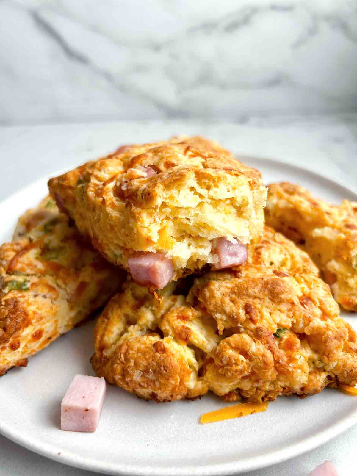 plate of ham and cheese scones with one with a bite taken out of it.