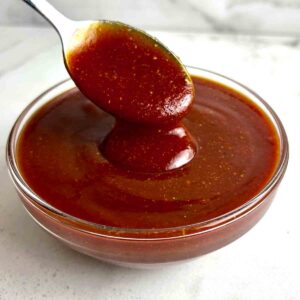 spoon lifting barbecue sauce from bowl.