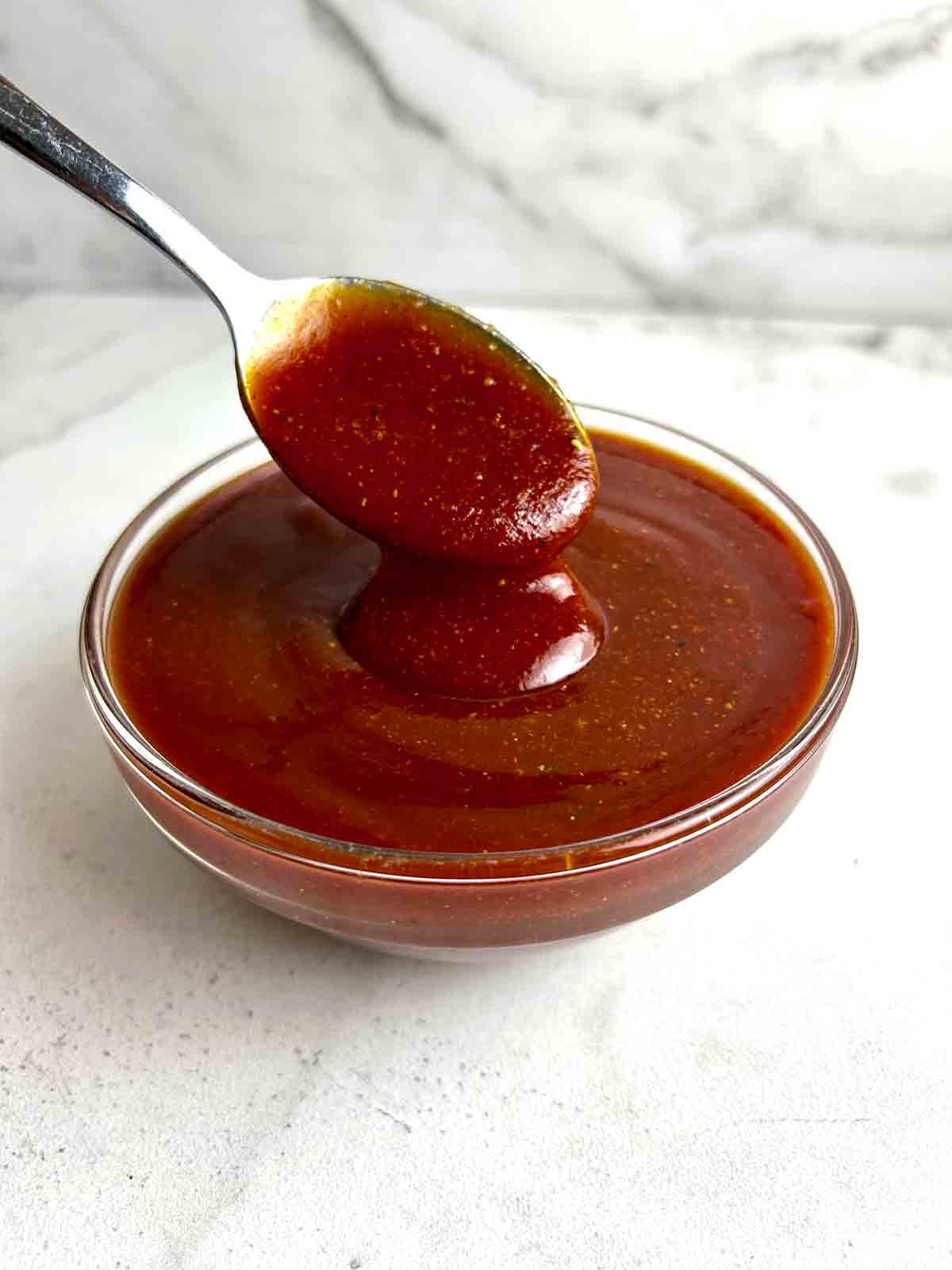 spoon lifting barbecue sauce from bowl.
