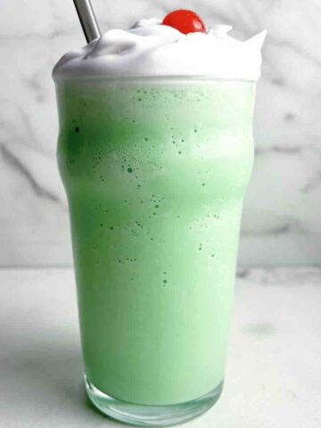 tall glass of shamrock shake with cream and cherry on top.