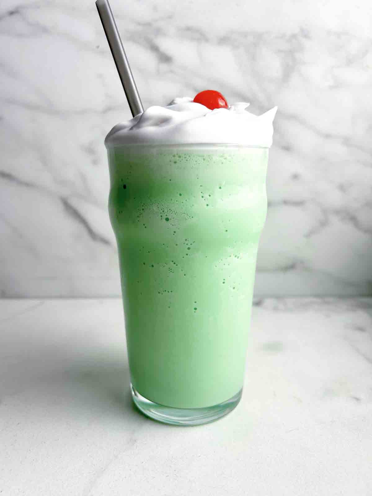 tall glass of shamrock shake with cream and cherry on top.