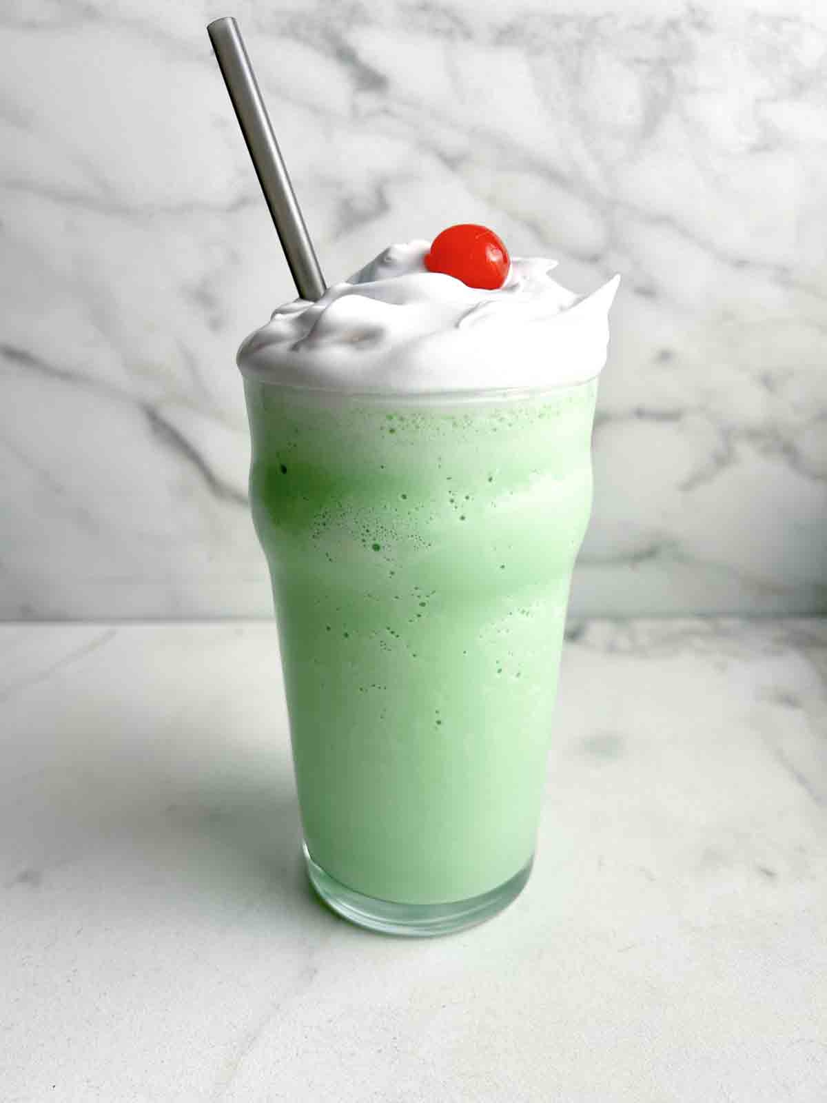tall glass of shamrock shake with cream and cherry on top.