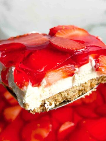 spatula lifting slice of strawberry pretzel salad from dish.