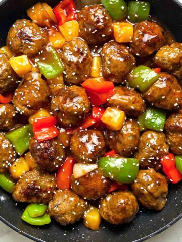 close up of sweet and sour meatballs in skillet.