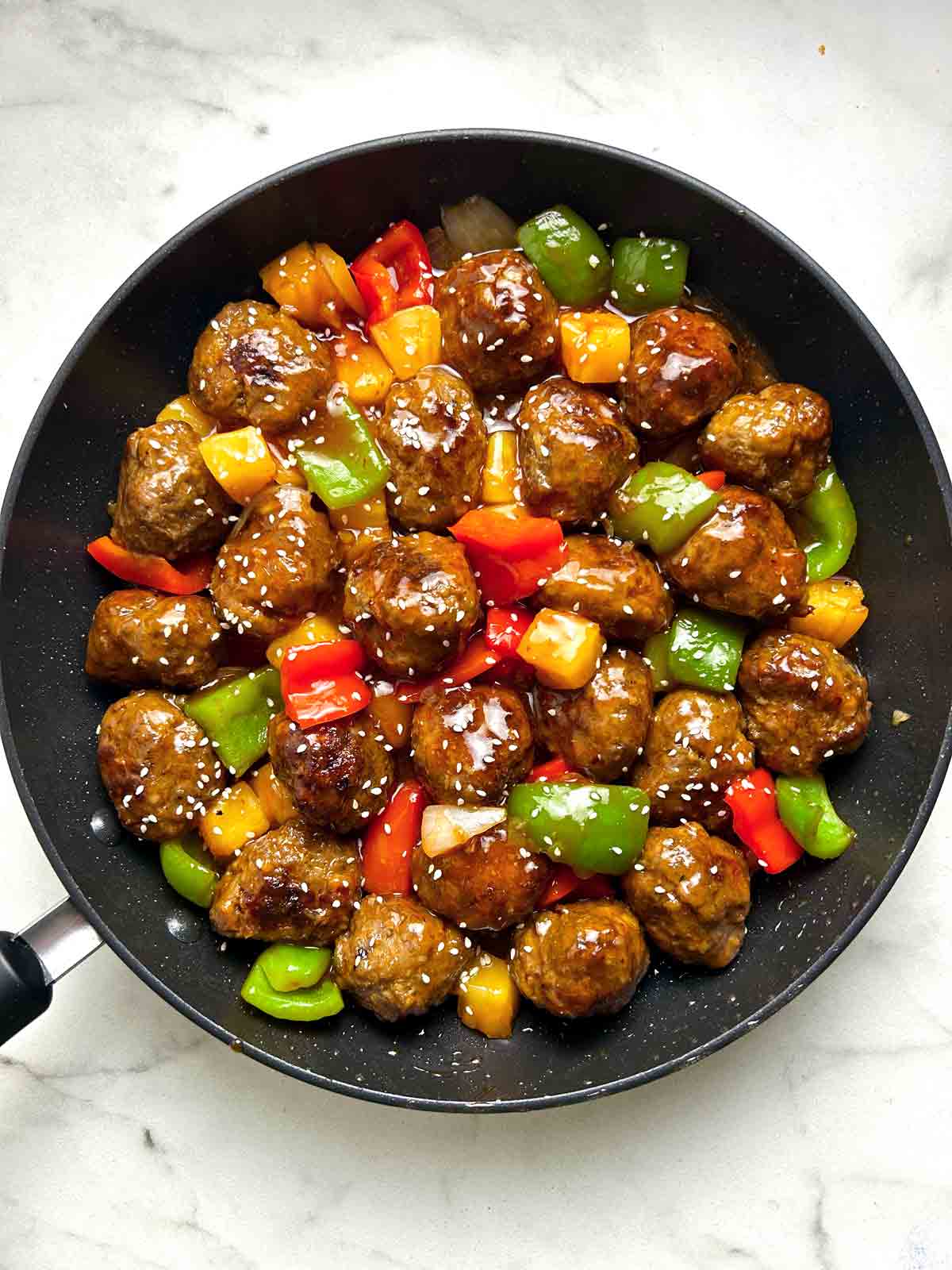 close up of sweet and sour meatballs in skillet.