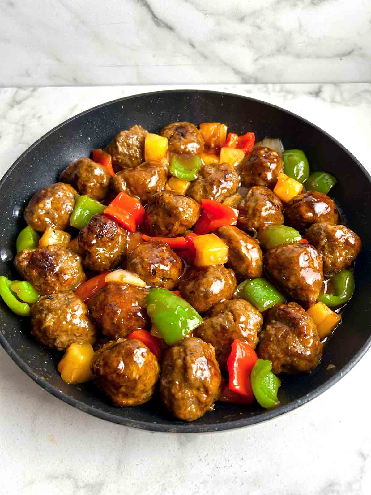 side view of sweet and sour meatballs in skillet.
