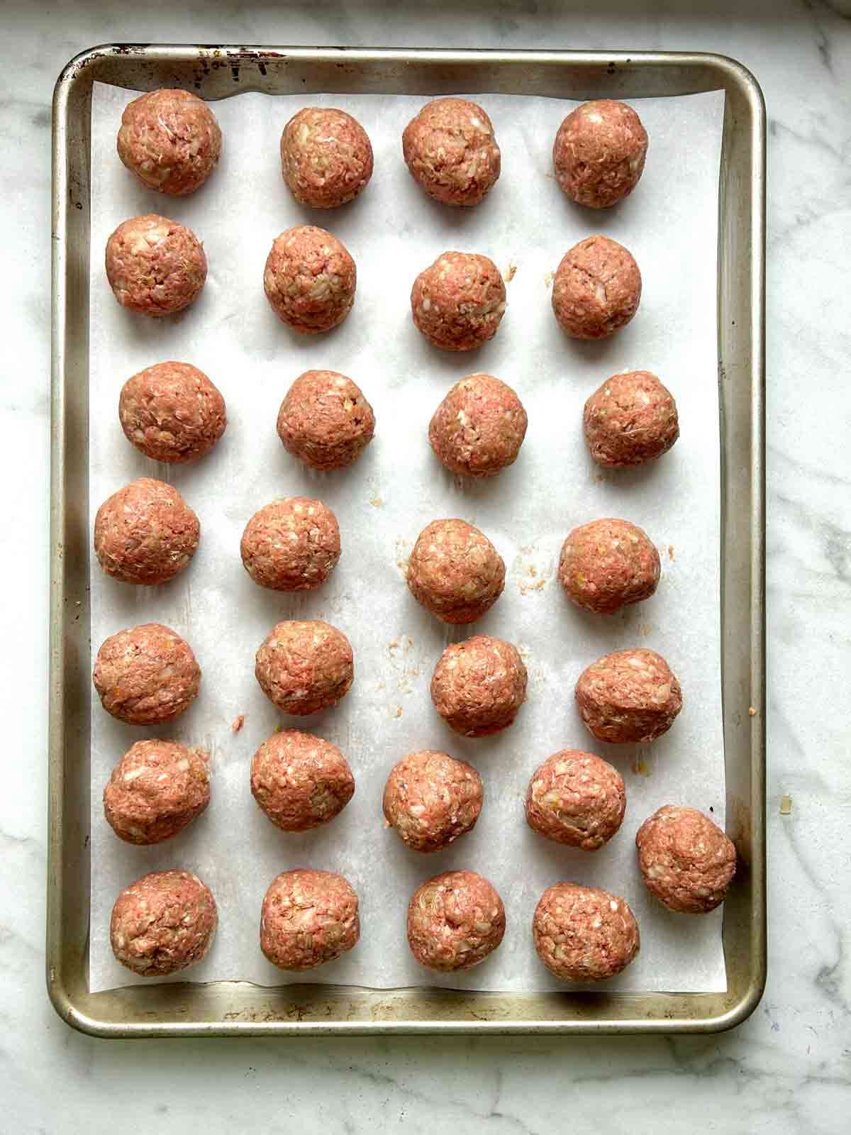 raw meatballs on baking sheet with parchment paper.