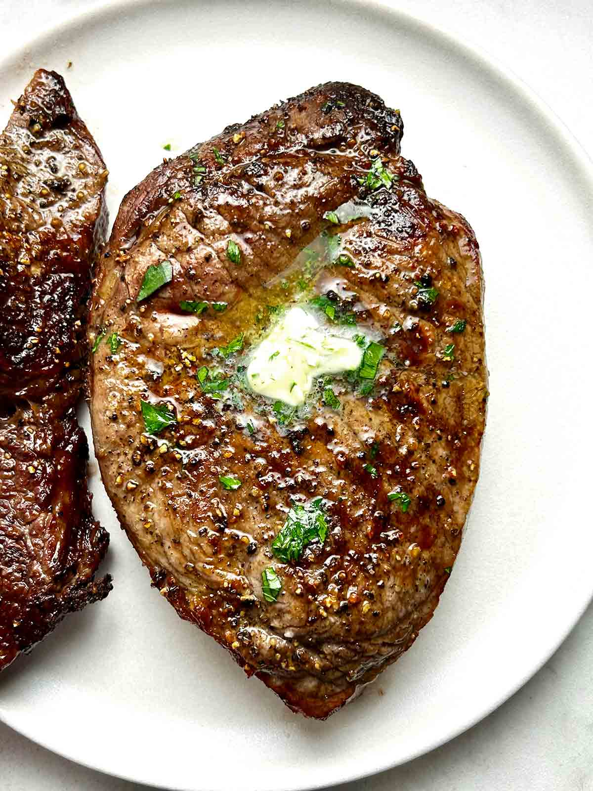 close up of air fried steak with pat of garlic butter on top.