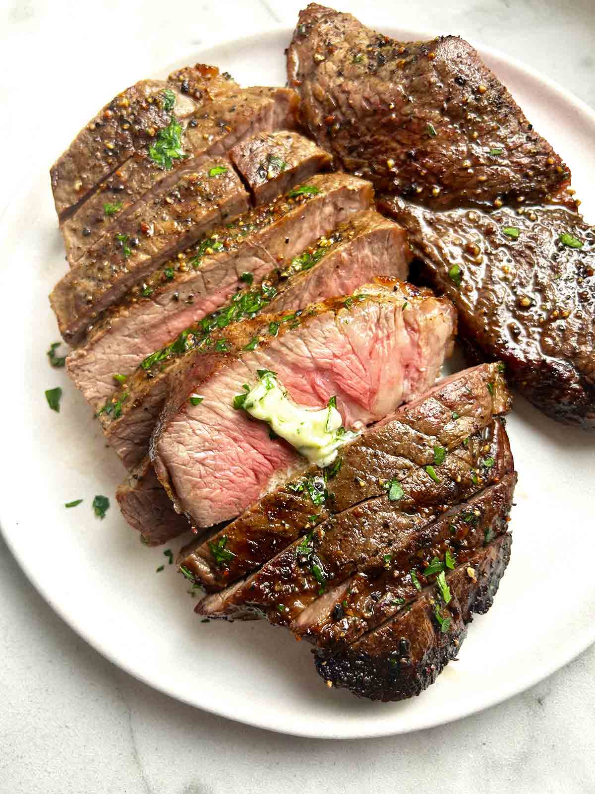 close up of steak sliced into pieces with melted butter on top.