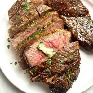 close up of steak sliced into pieces with melted butter on top.