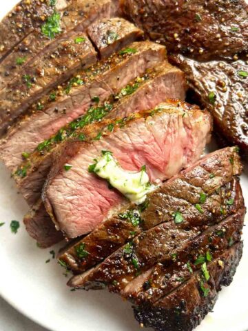 close up of steak sliced into pieces with melted butter on top.