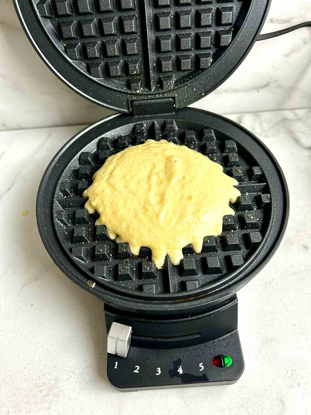 batter scooped into center of waffle maker.