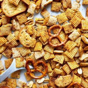 close up spatula lifting of Chex mix from pan.