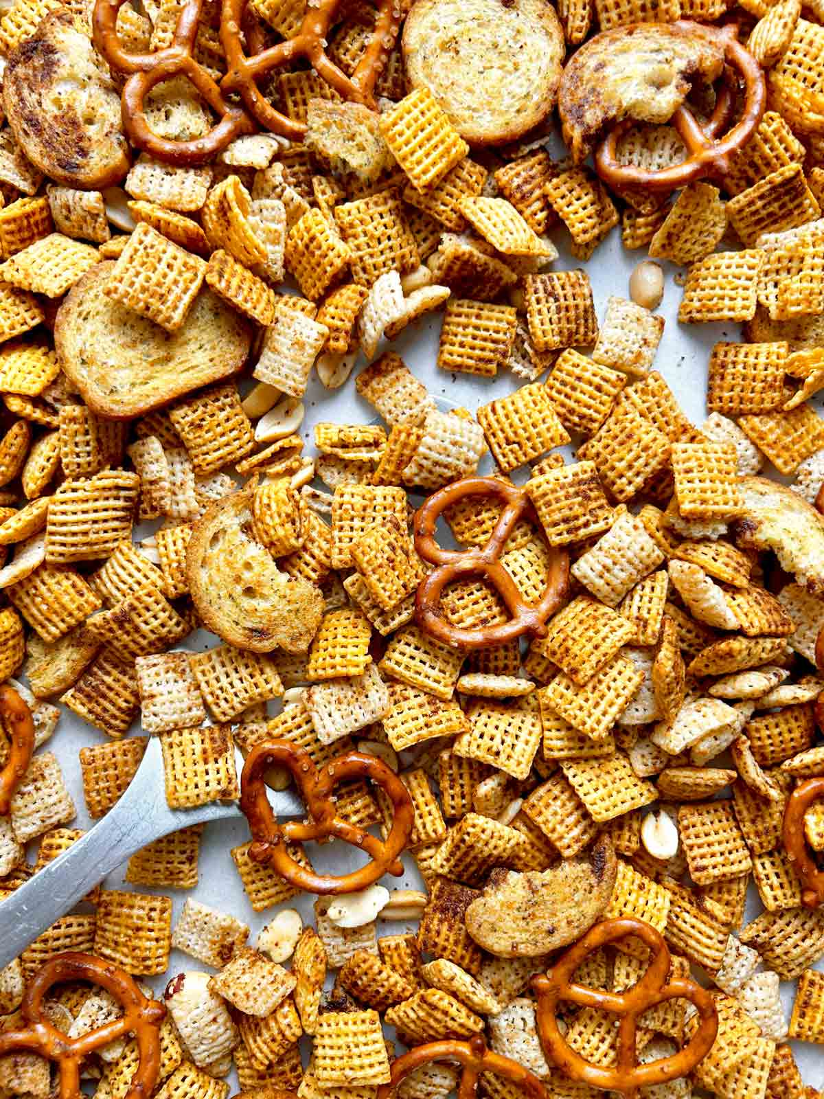 close up spatula lifting of Chex mix from pan.
