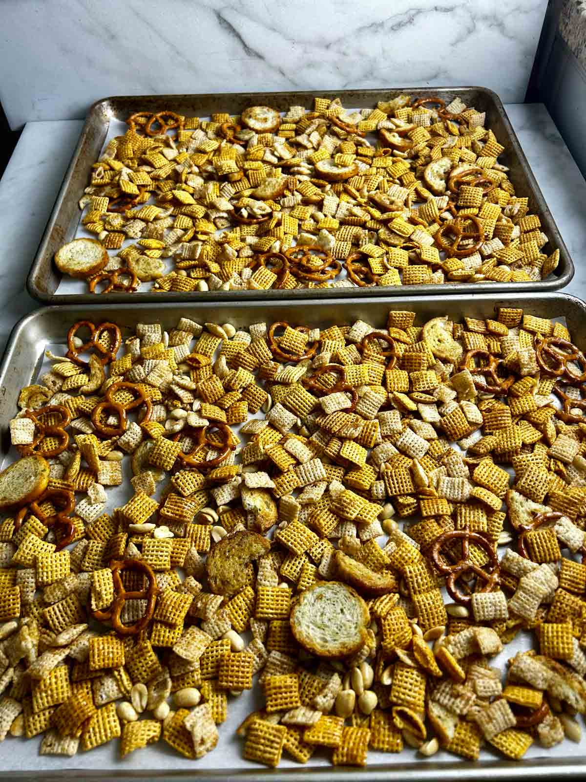 Chex mix spread between two large baking sheets.