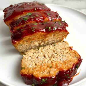 close up of slice chicken meatloaf on plate.