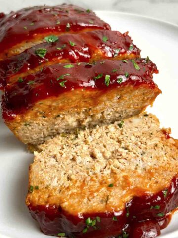 close up of slice chicken meatloaf on plate.
