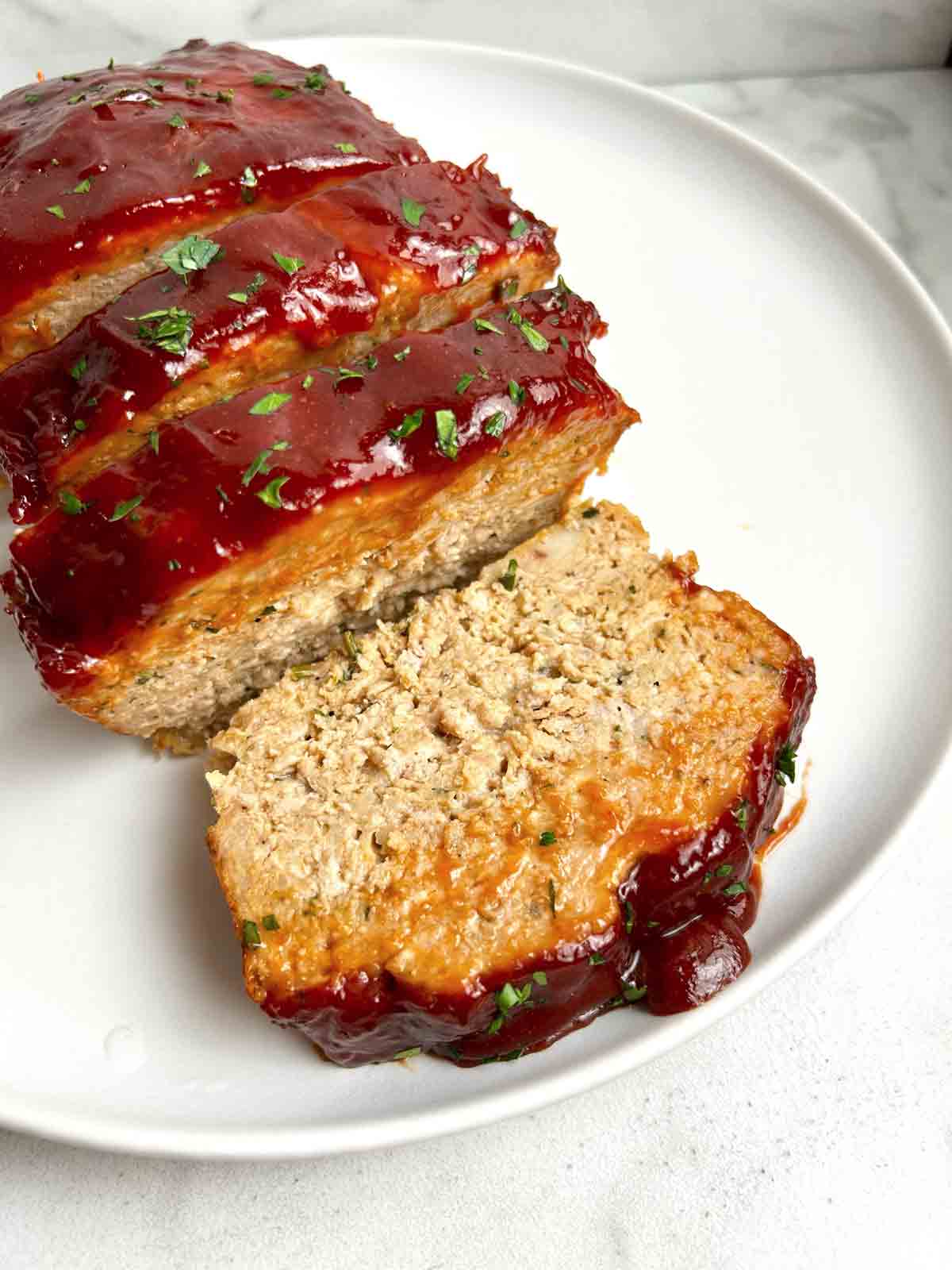 close up of slice chicken meatloaf on plate.