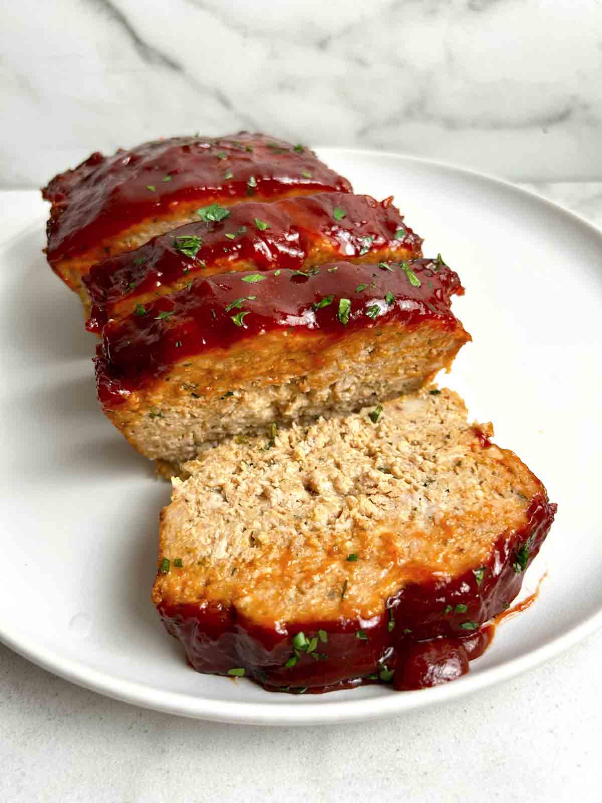 close up of slice chicken meatloaf on plate.