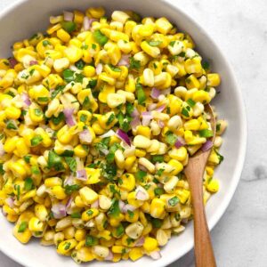 Chipotle corn salsa in white bowl with spoon in it.