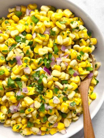 Chipotle corn salsa in white bowl with spoon in it.