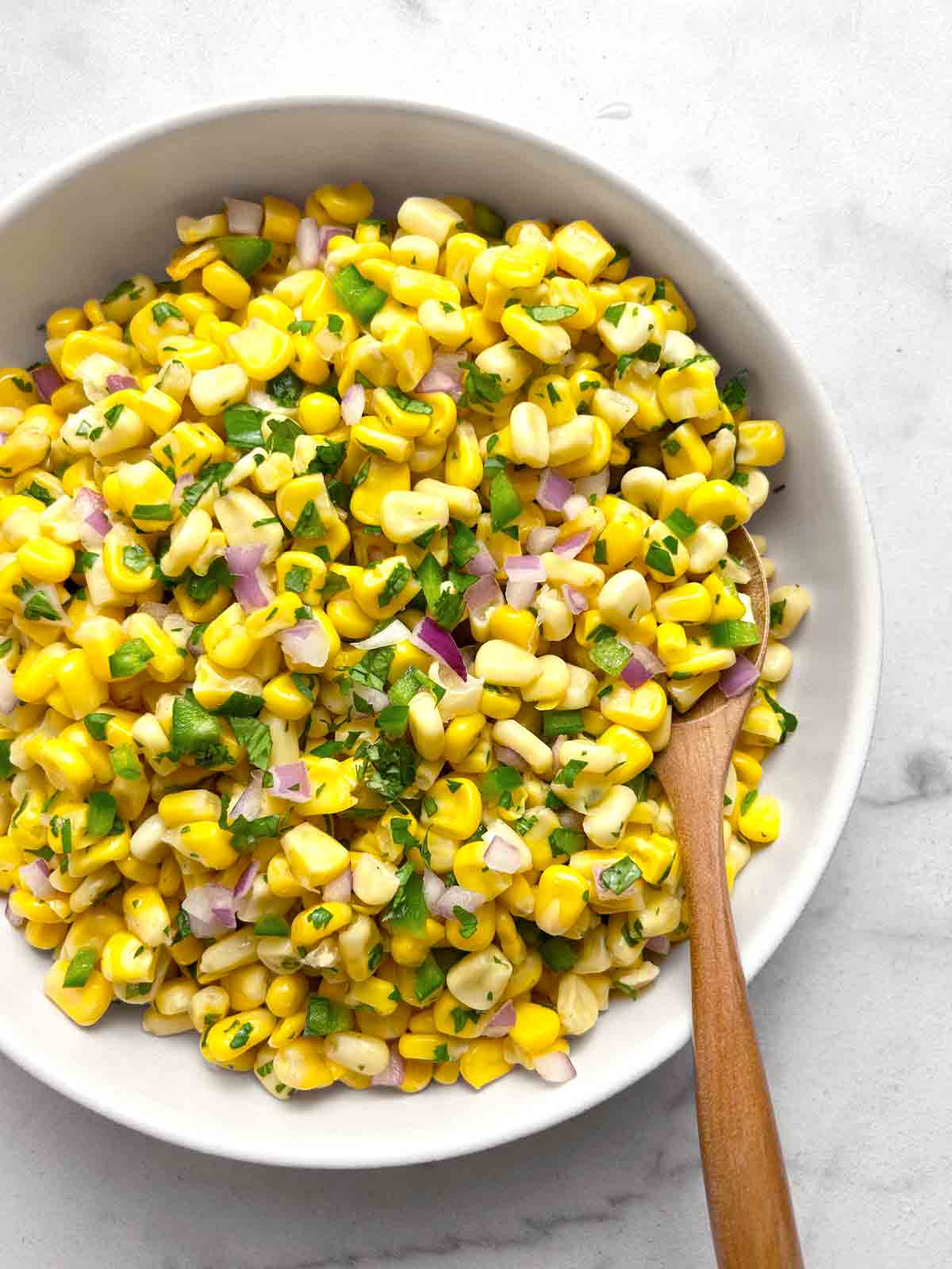 Chipotle corn salsa in white bowl with spoon in it.