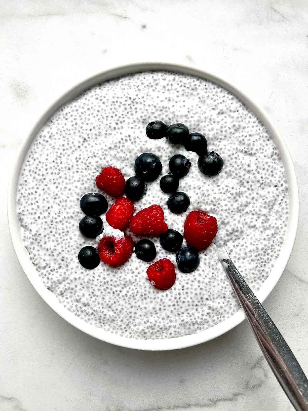 bowl of coconut chia pudding with berries on top.
