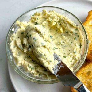 knife lifting garlic butter our of bowl.