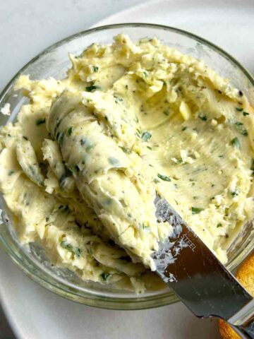 knife lifting garlic butter our of bowl.