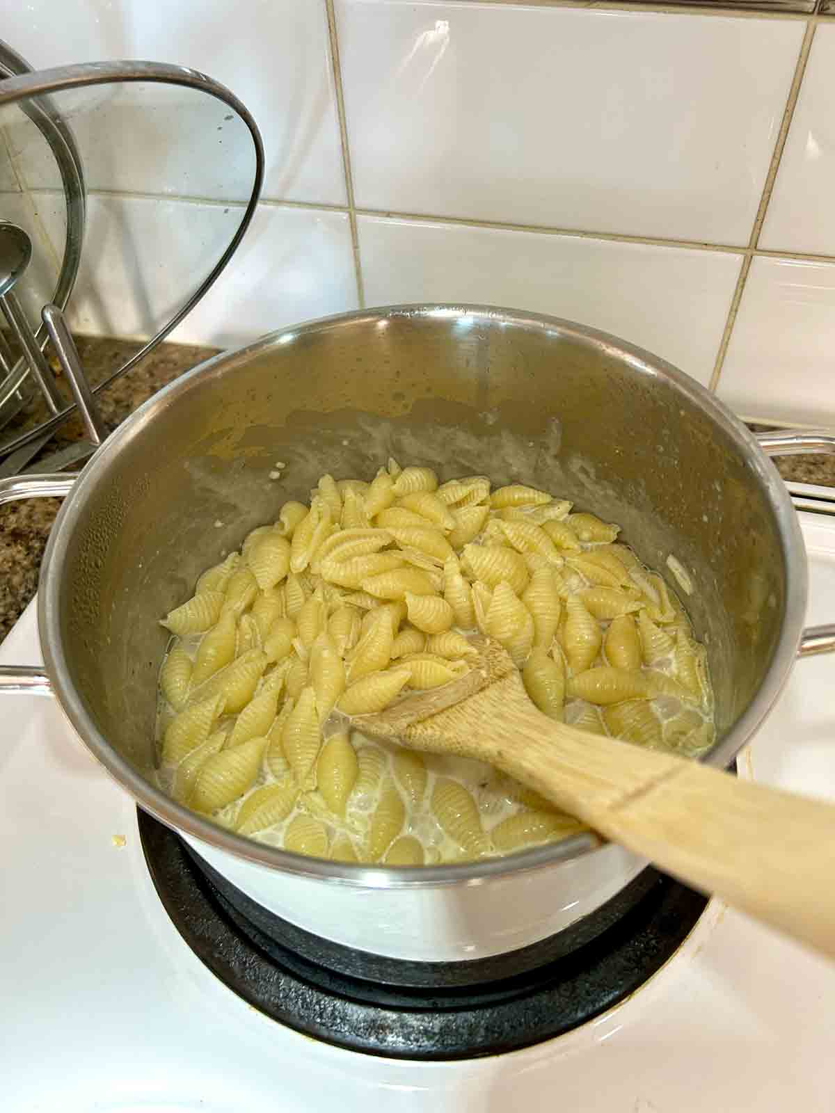 pasta being cooked in sauce; most of the sauce is absorbed into the pasta.