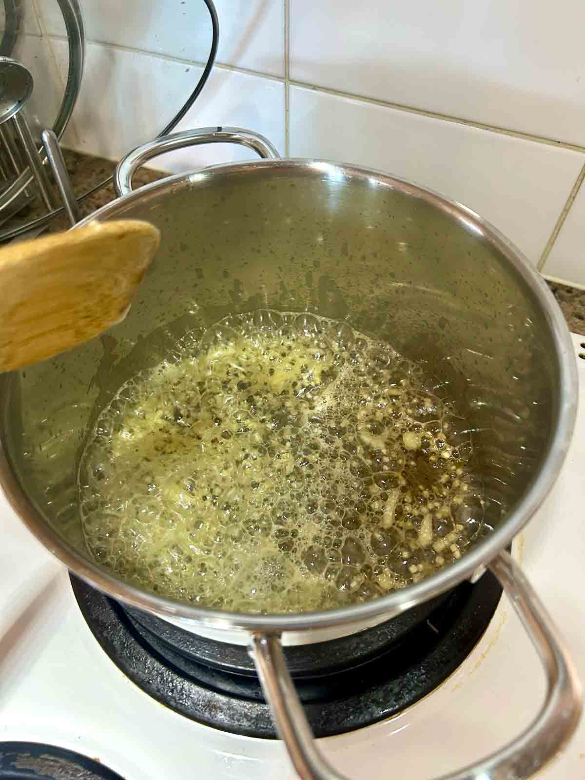 garlic being sautéed in butter in pot.