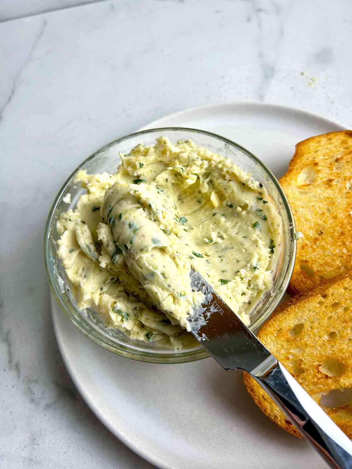 knife lifting garlic butter our of bowl.