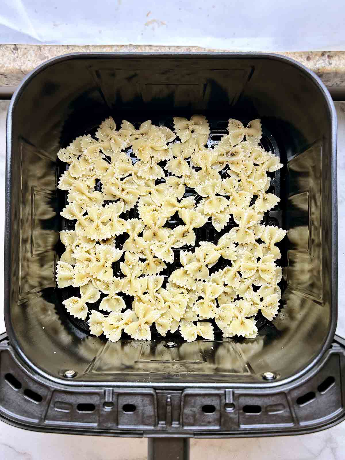 overhead shot of uncooked pasta chips in air fryer basket.