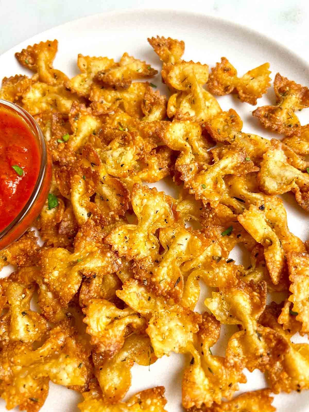 close up of air fried pasta chips on plate.