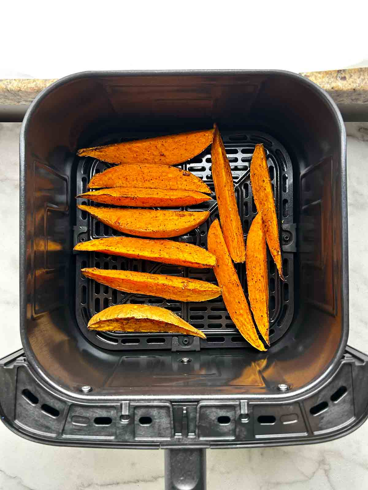 sweet potato wedges still in basket after air-frying.