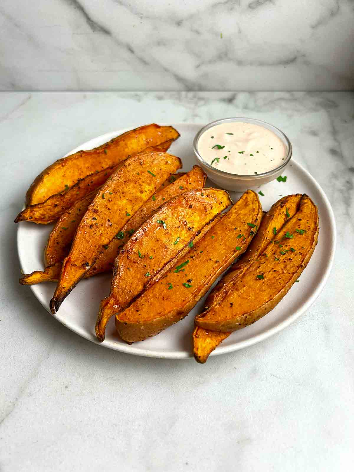air-fried sweet potato wedges on plate with bowl of chipotle sauce.