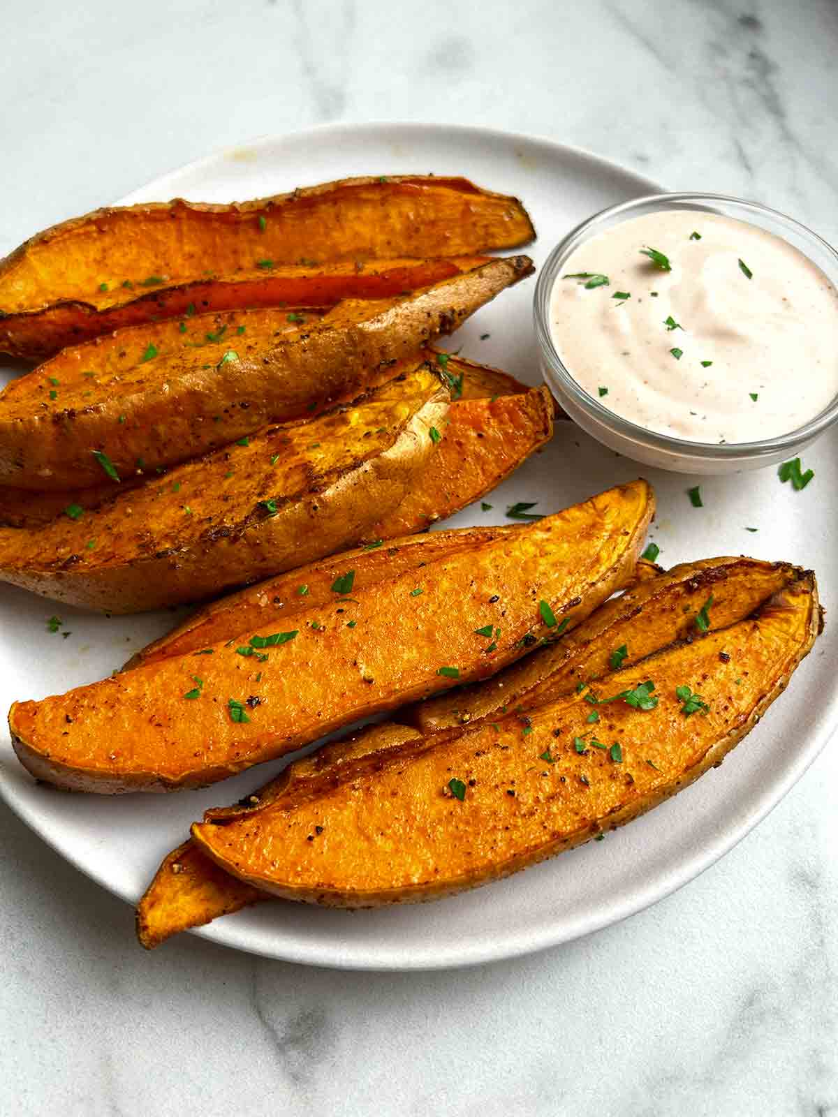 air-fried sweet potato wedges on plate with bowl of chipotle sauce.