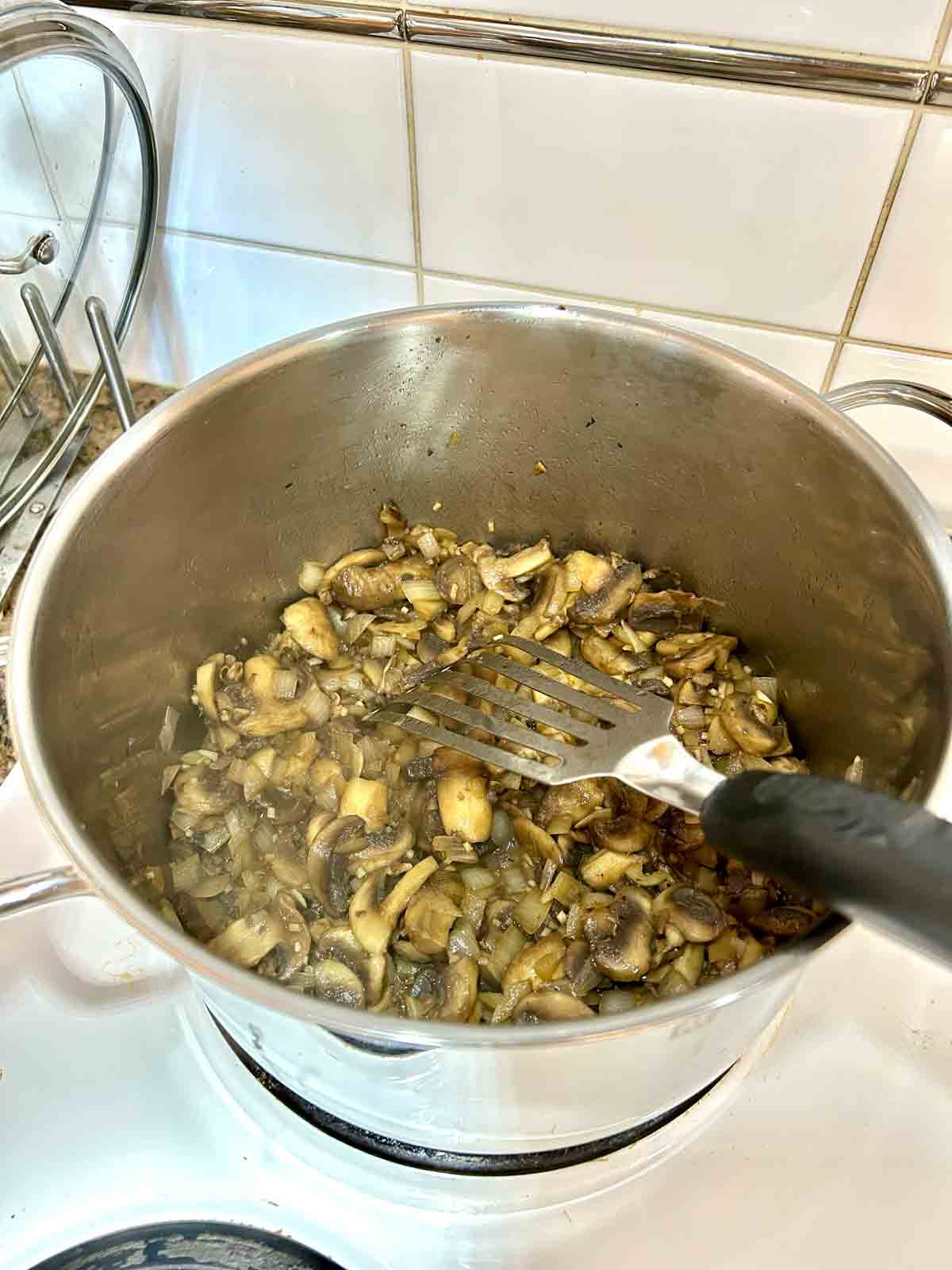 mushrooms, onions, and garlic being sautéed in large pot.