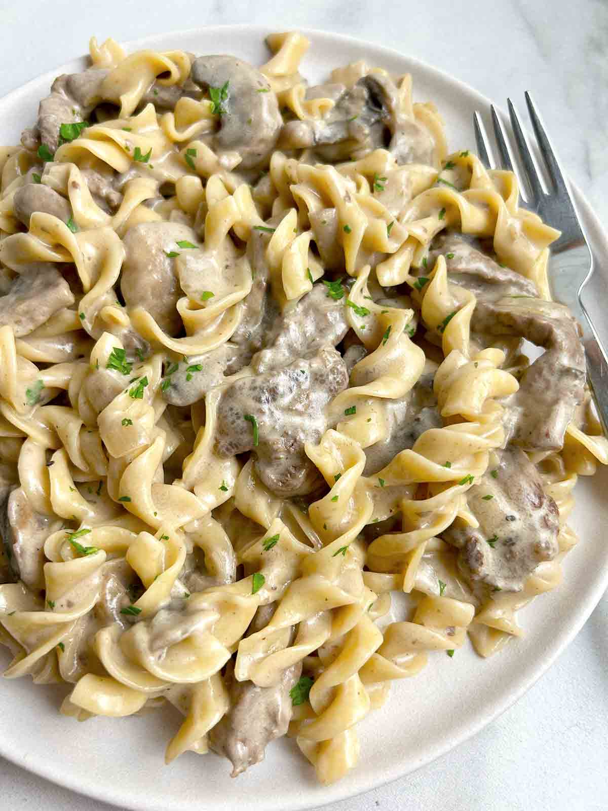 close up of beef stroganoff on plate with fork.